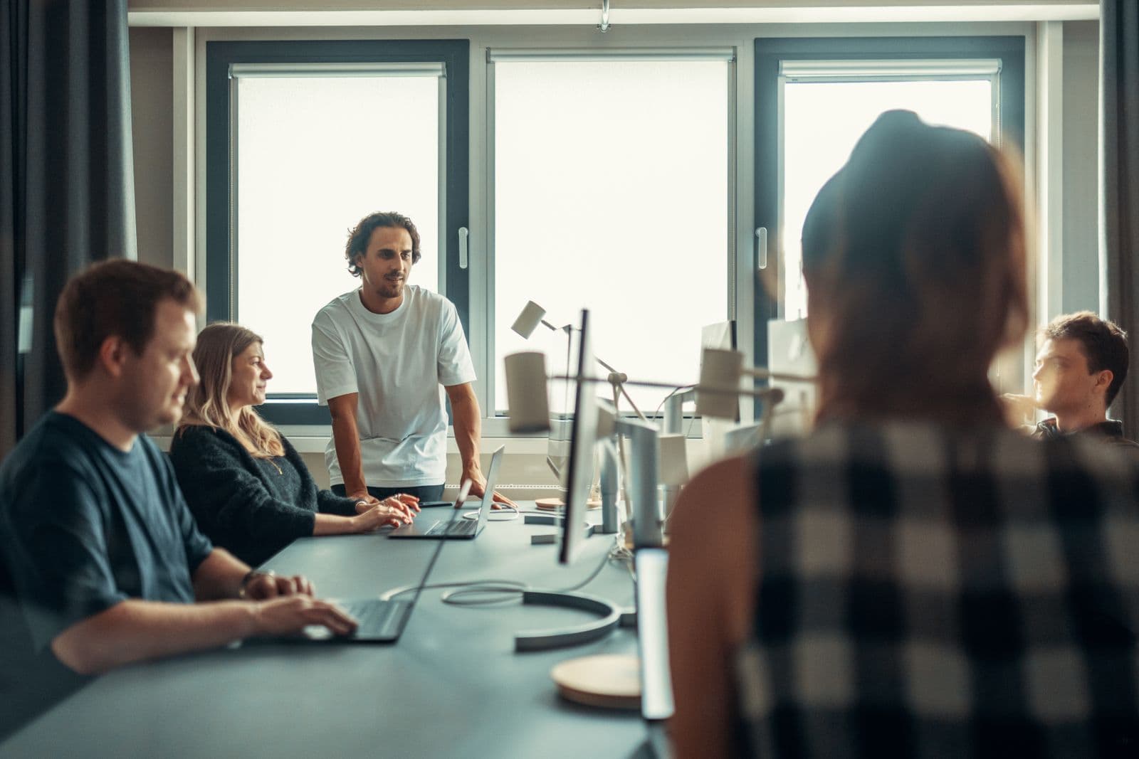 Hiring team gathered around laptops in a modern office, planning an ERP recruitment shortlist